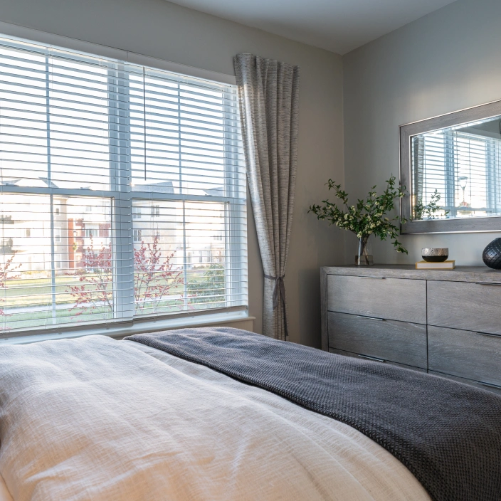 Bedroom corner view showing large window dresser mirror and minimalist gray decorative touches