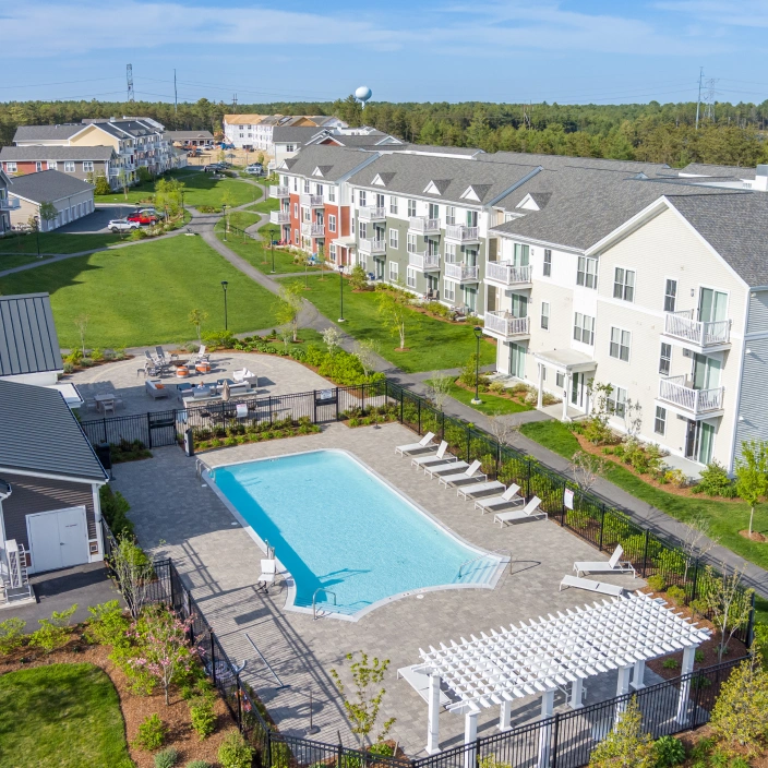 Aerial view of modern apartment community with outdoor swimming pool and landscaped green courtyard