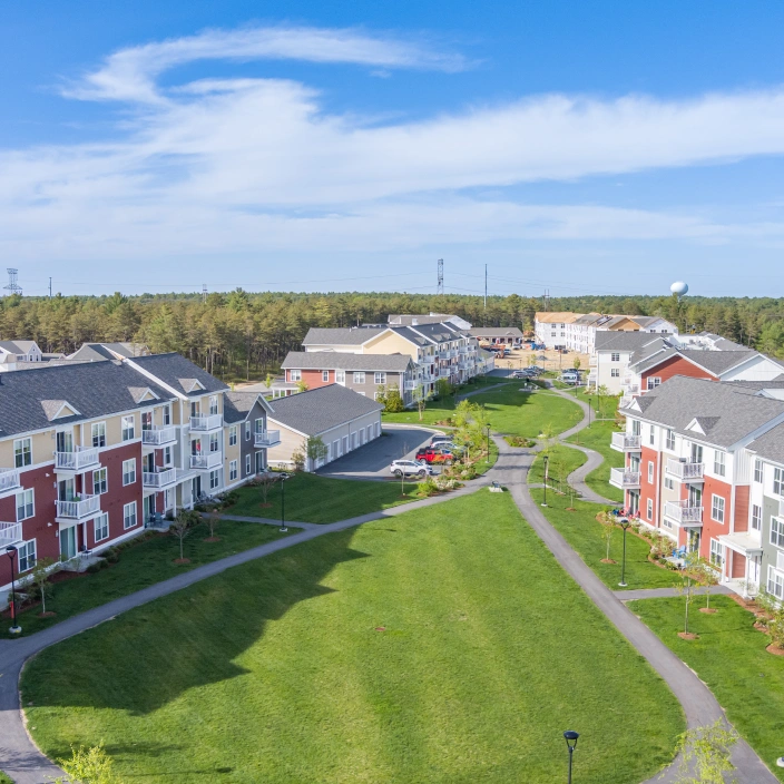 Expansive green courtyard between modern apartment buildings with walking paths and landscaped lawns