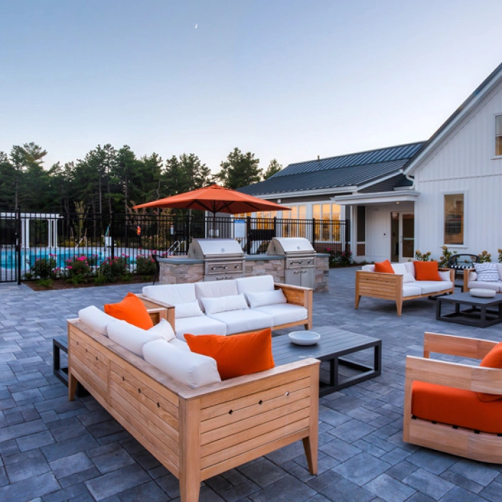 Cozy outdoor lounge area with cushioned seating, umbrellas, and grilling stations near community pool