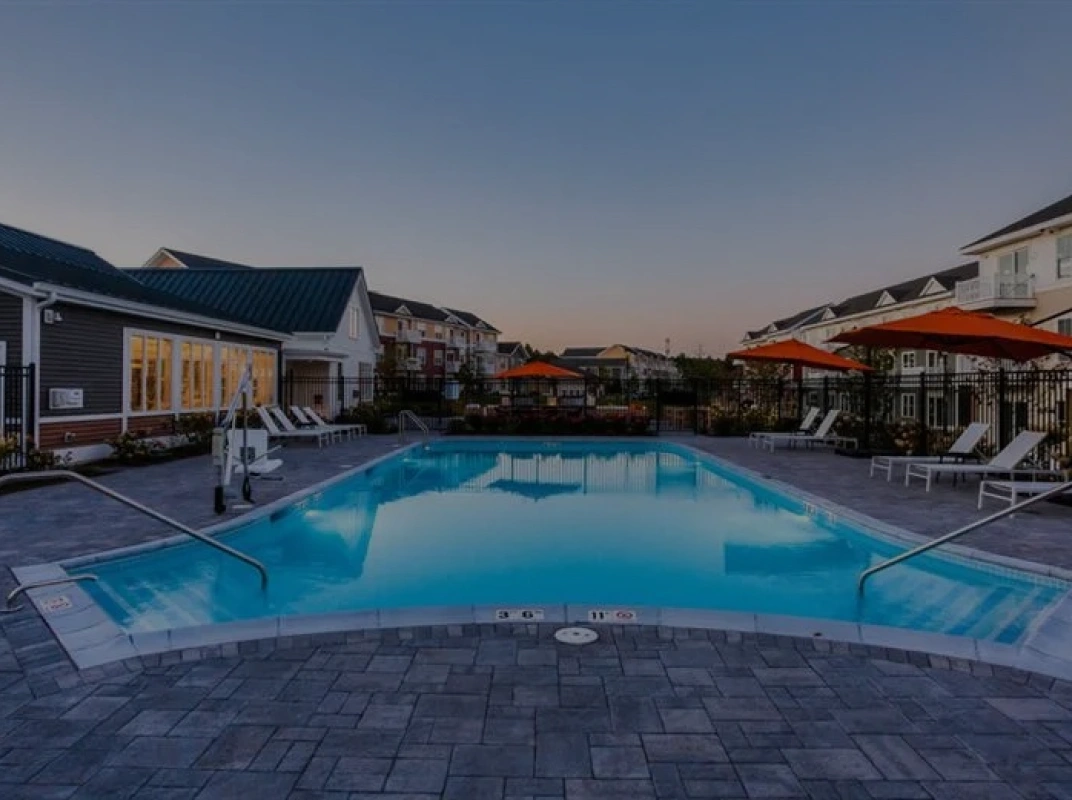 Sparkling outdoor swimming pool surrounded by lounge chairs and bright orange umbrellas