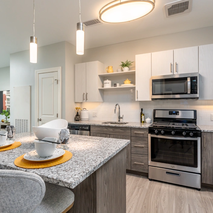 Contemporary kitchen with granite countertops, stainless steel appliances, and modern pendant lighting