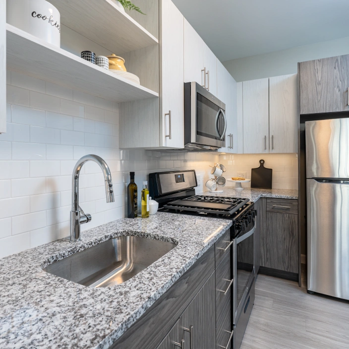 Modern kitchen with granite countertops, stainless steel appliances, and sleek two-tone cabinetry design