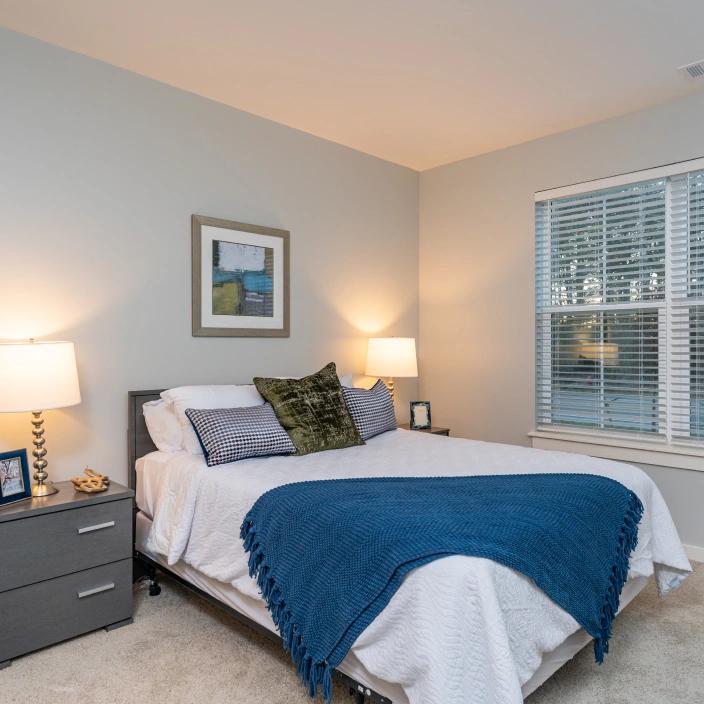Cozy bedroom with soft lighting, decorative pillows, and framed wall art above bed