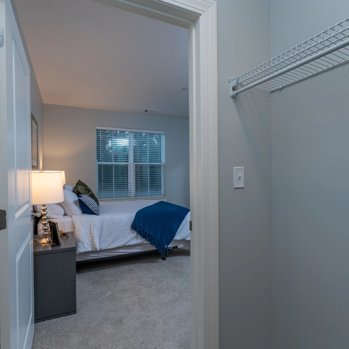 Bedroom entrance night view from empty closet space with bed and large window visible