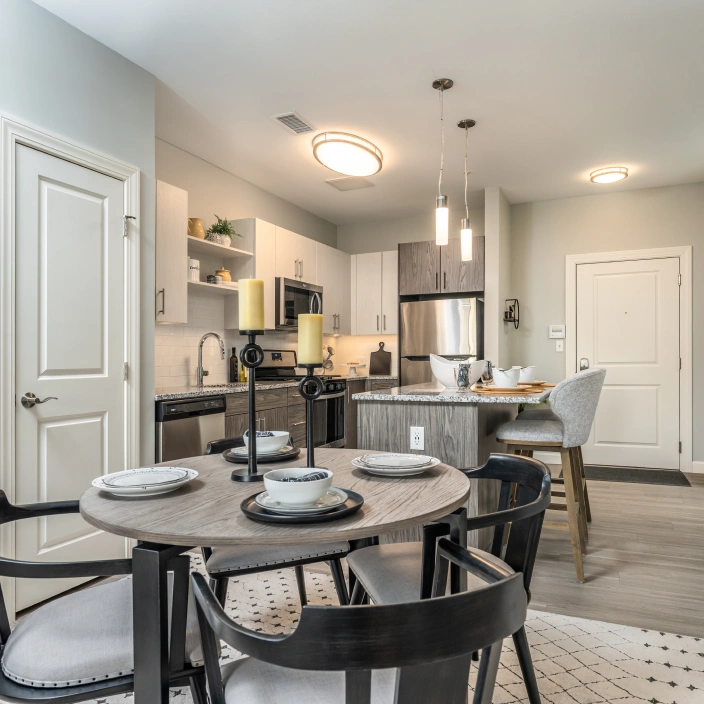 Modern apartment kitchen and dining space with pendant lights and stainless steel appliances