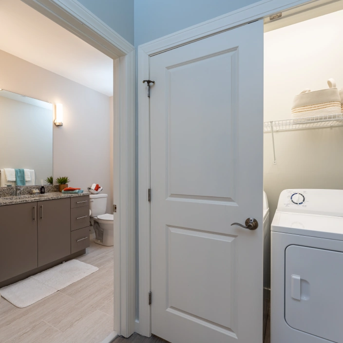 Practical bathroom-laundry combo area featuring granite counters and full-size washer