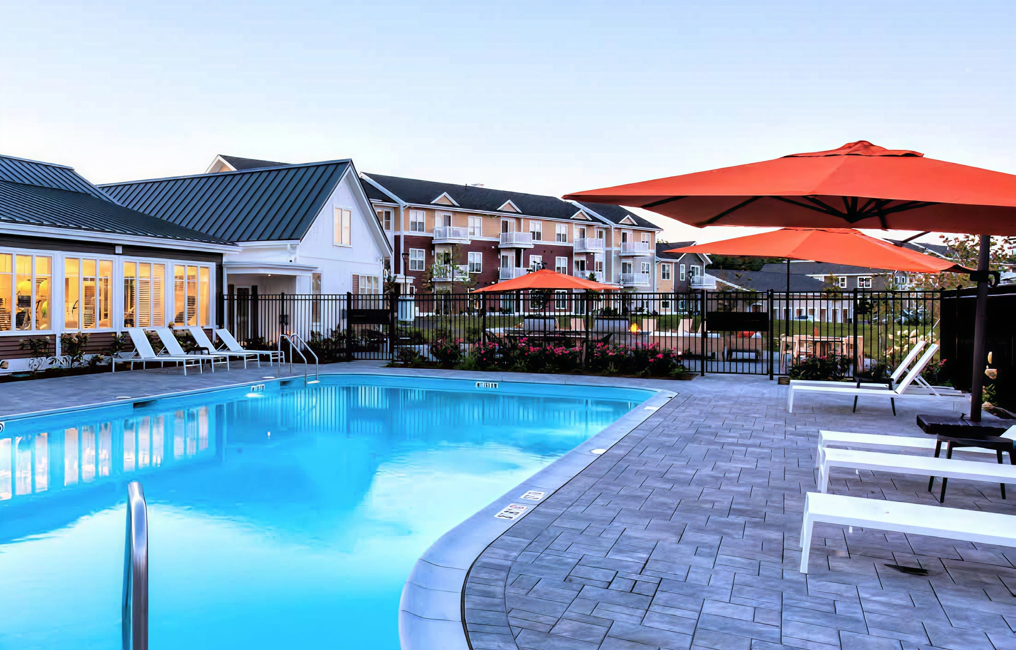 Luxury apartment pool with orange umbrellas, sunny atmosphere, and stylish outdoor furnishings