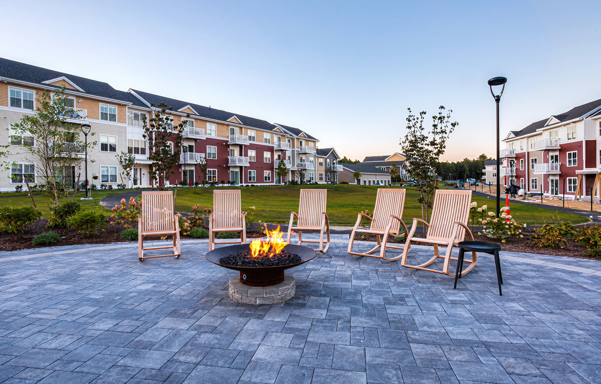 Outdoor fire pit area surrounded by wooden rocking chairs in a landscaped courtyard
