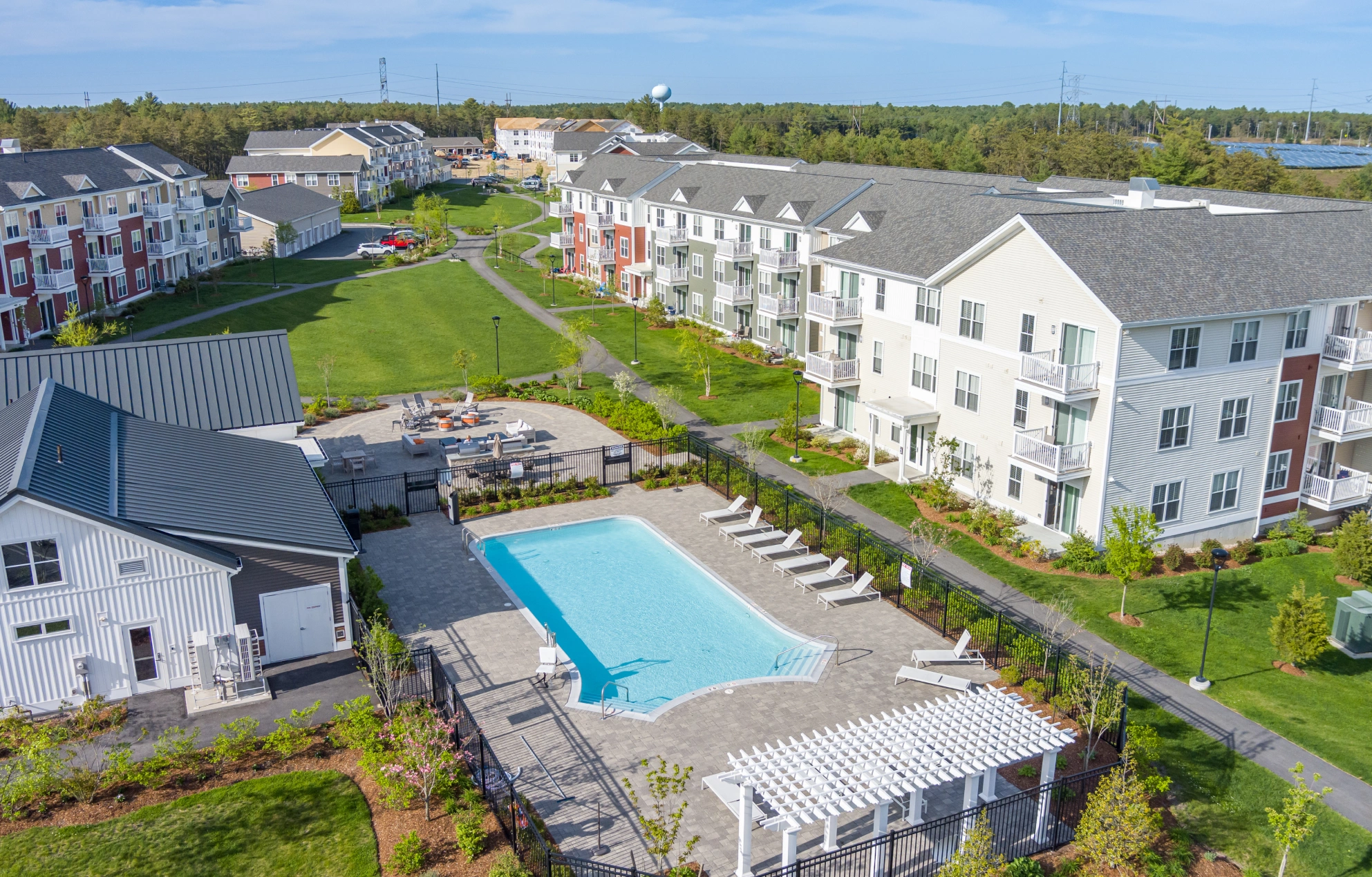 Aerial view of apartment community with swimming pool, green courtyard, and modern residential buildings