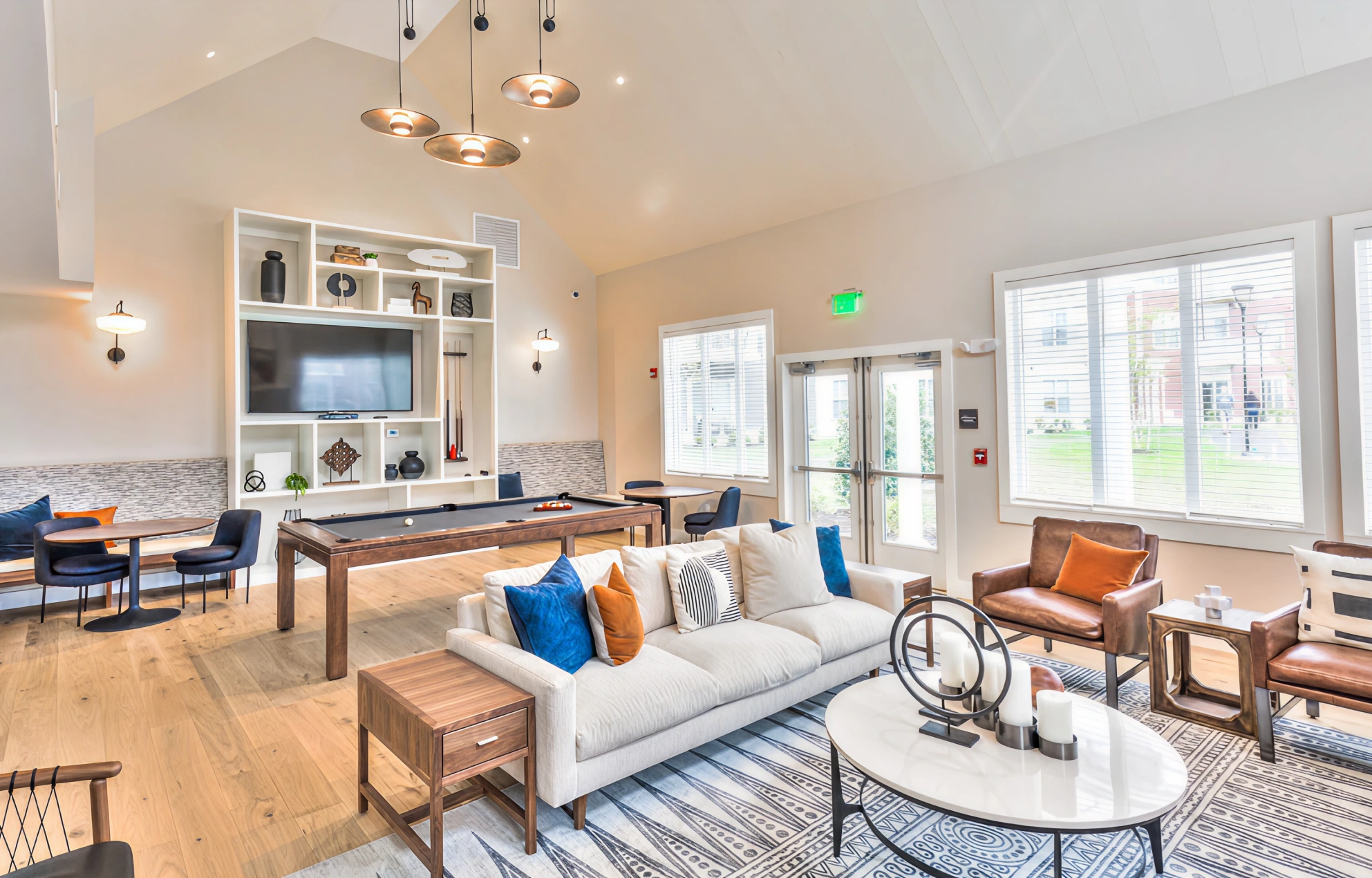 Modern clubhouse interior with pool table, bright windows, and stylish contemporary furniture